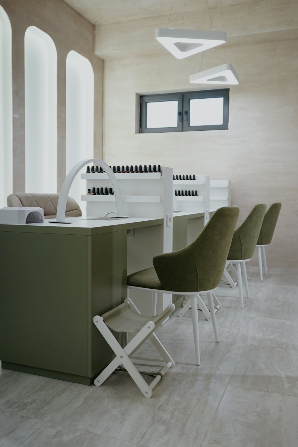 Moderno salone per unghie con postazioni per manicure verdi e scaffali per smalti.